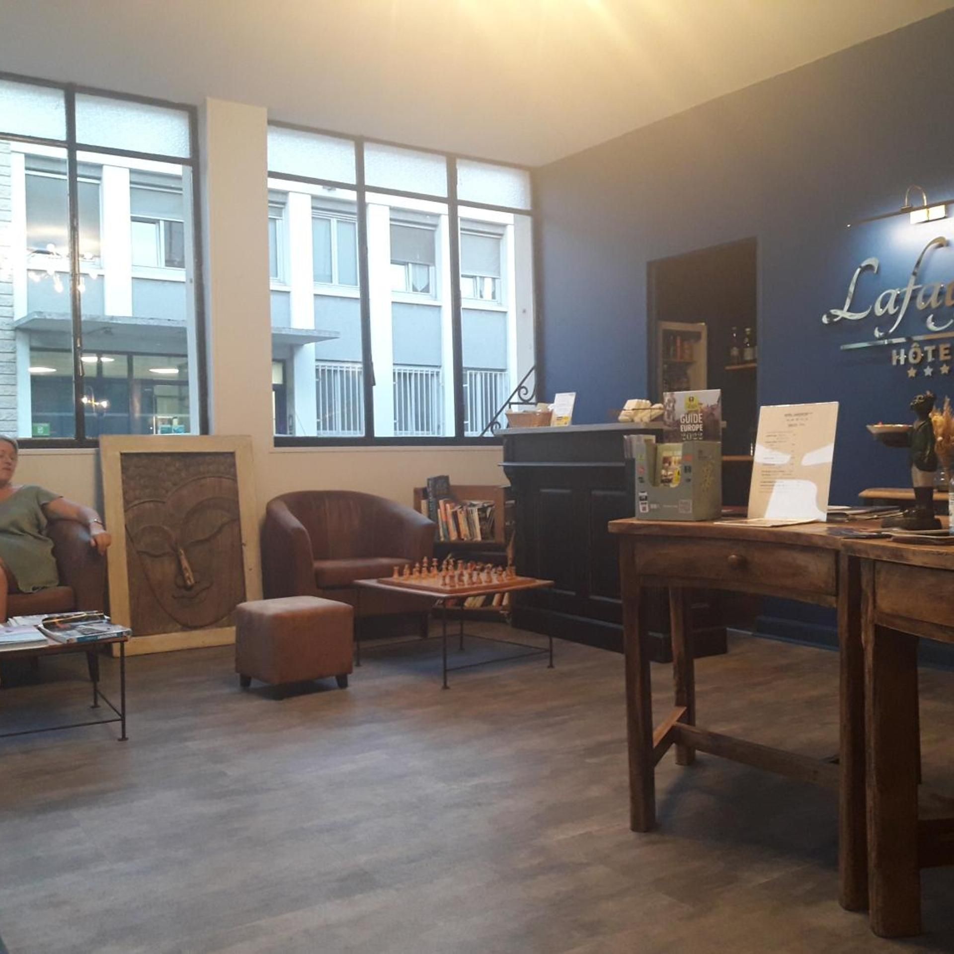 Un hall d’hôtel avec une table d’échecs, un canapé et une grande fenêtre donnant sur le bâtiment.