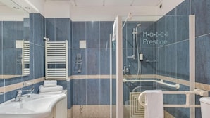 A modern bathroom with a glass shower enclosure, a white sink, and a toilet.