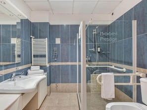 Un baño moderno con cabina de ducha de vidrio, lavamanos blanco y retrete.