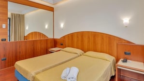 A hotel room with two beds, a wooden headboard, a desk, and a mirror.