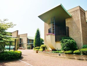 Um edifício moderno com design arquitetônico único, apresentando um beirado saliente e fachada de tijolos.