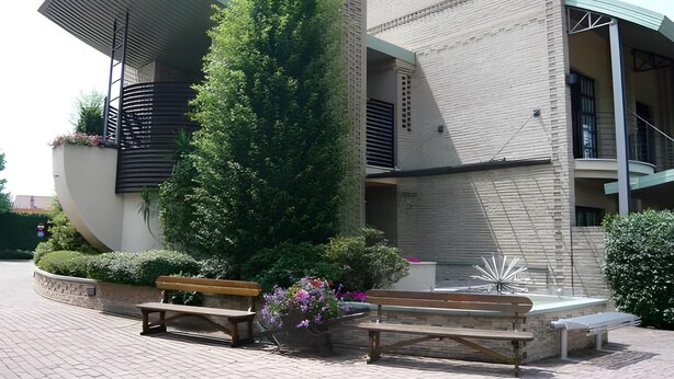 A modern building with a unique architectural design, featuring a prominent vertical garden and outdoor seating areas.