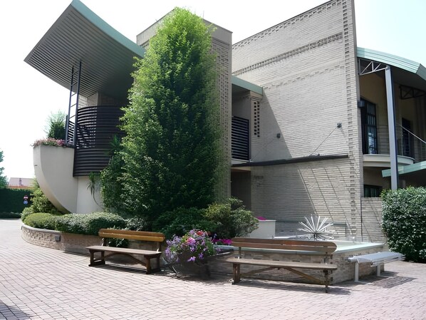 Un edificio moderno con un diseño arquitectónico único, que cuenta con un prominente jardín vertical y zonas de estar al aire libre.