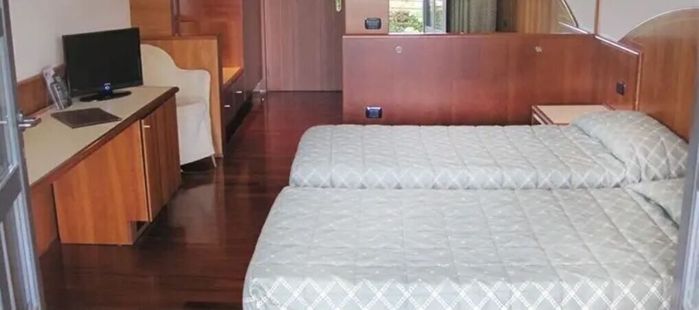 A bedroom with a bed, a desk, and a television.