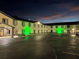A hotel with a parking lot, multiple rooms, and a building with green lighting.