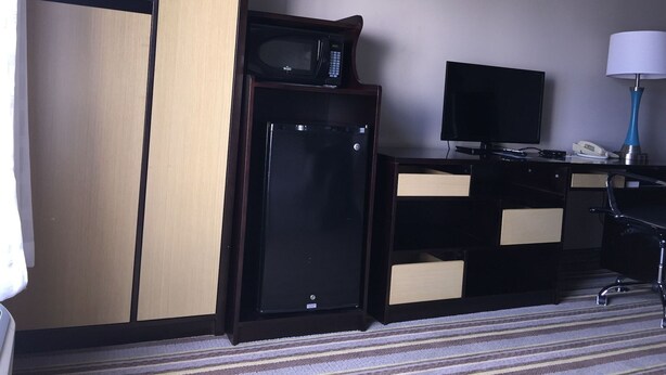 A hotel room with a desk, a television, a microwave, a telephone, and a lamp. - Delavan Inn and Suites (Delavan)