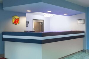 A reception desk with a blue and white color scheme, a 'Super 8' sign, and a framed certificate on the wall.