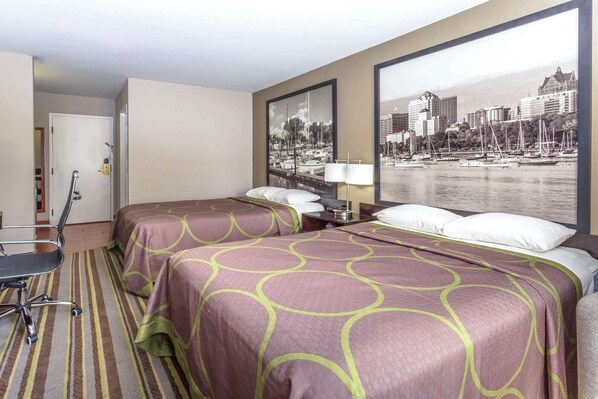 A hotel room with two beds, a desk, a chair, and a large window with a cityscape view. - Delavan Inn and Suites (Delavan)