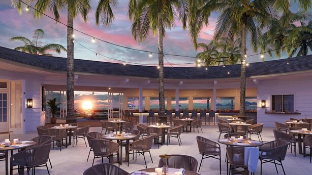 An outdoor dining area with multiple tables and chairs, palm trees, and a sunset view. - The Naples Beach Hotel and Golf Club (Naples)
