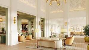A spacious lobby with a high ceiling, ornate wall designs, and a central seating area with multiple lamps. - The Naples Beach Hotel and Golf Club (Naples)