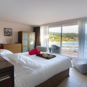 A hotel room with a bed, a desk, a wardrobe, and a view of the sea. - Hotel Le Golfe (Serra-di-Ferro)