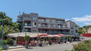 A multi-story hotel with outdoor seating and a covered area. - Le Golfe, Piscine & Spa Casanera (Serra-di-Ferro)