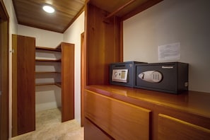 Quarto com escrivaninha de madeira, cofre e porta que dá para um armário.