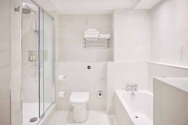 A modern bathroom with a glass-enclosed shower, a toilet, and a bathtub.