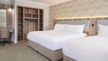 Una habitación de hotel con dos camas, un armario, un escritorio y un espejo.