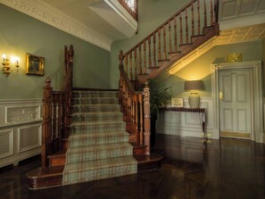 A grand staircase with a plaid carpet, a wooden railing, and a sign indicating the location of toilets. - Bunratty Castle Hotel & Leisure Club, BW Premier Collection (Bunratty)