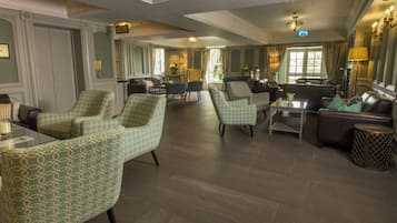Un amplio hall de hotel con varias zonas de estar, incluidas sofás y sillones, y una mesa de centro.