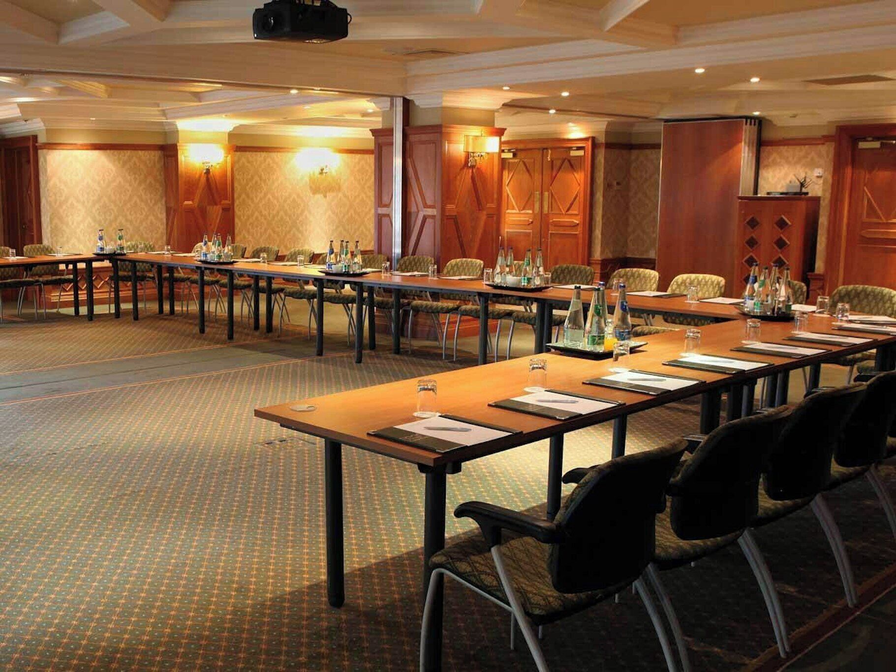 Une salle de conférence équipée de longues tables, de chaises et d’un écran de projection.