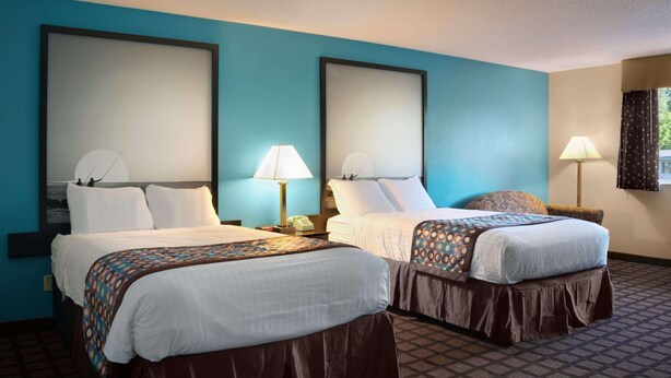 Habitación de hotel con dos camas, una pared azul decorativa y piso estampado.