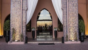 A building with a large archway, patterned walls, and a reflective glass entrance. - Adam Park Marrakech Hotel & Spa (Marrakech)