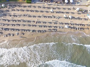 En strand med rader av parasoller och strandstolar, vilket tyder på att det är ett område med hotell och andra faciliteter för strandgäster.