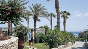 A man walking on a stone pathway surrounded by palm trees and greenery. - Ikaros Beach Luxury Resort and Spa - Adults Only (Hersonissos)
