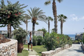 A man walking on a stone pathway surrounded by palm trees and greenery. - Ikaros Beach Luxury Resort and Spa - Adults Only (Hersonissos)