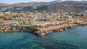 A coastal town with buildings, a rocky shoreline, and clear blue water. - Ikaros Beach Luxury Resort and Spa - Adults Only (Hersonissos)