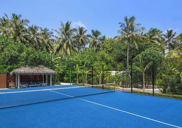 A blue tennis court surrounded by lush greenery and palm trees. - The Halcyon Private Isles Maldives (Meradhoo)