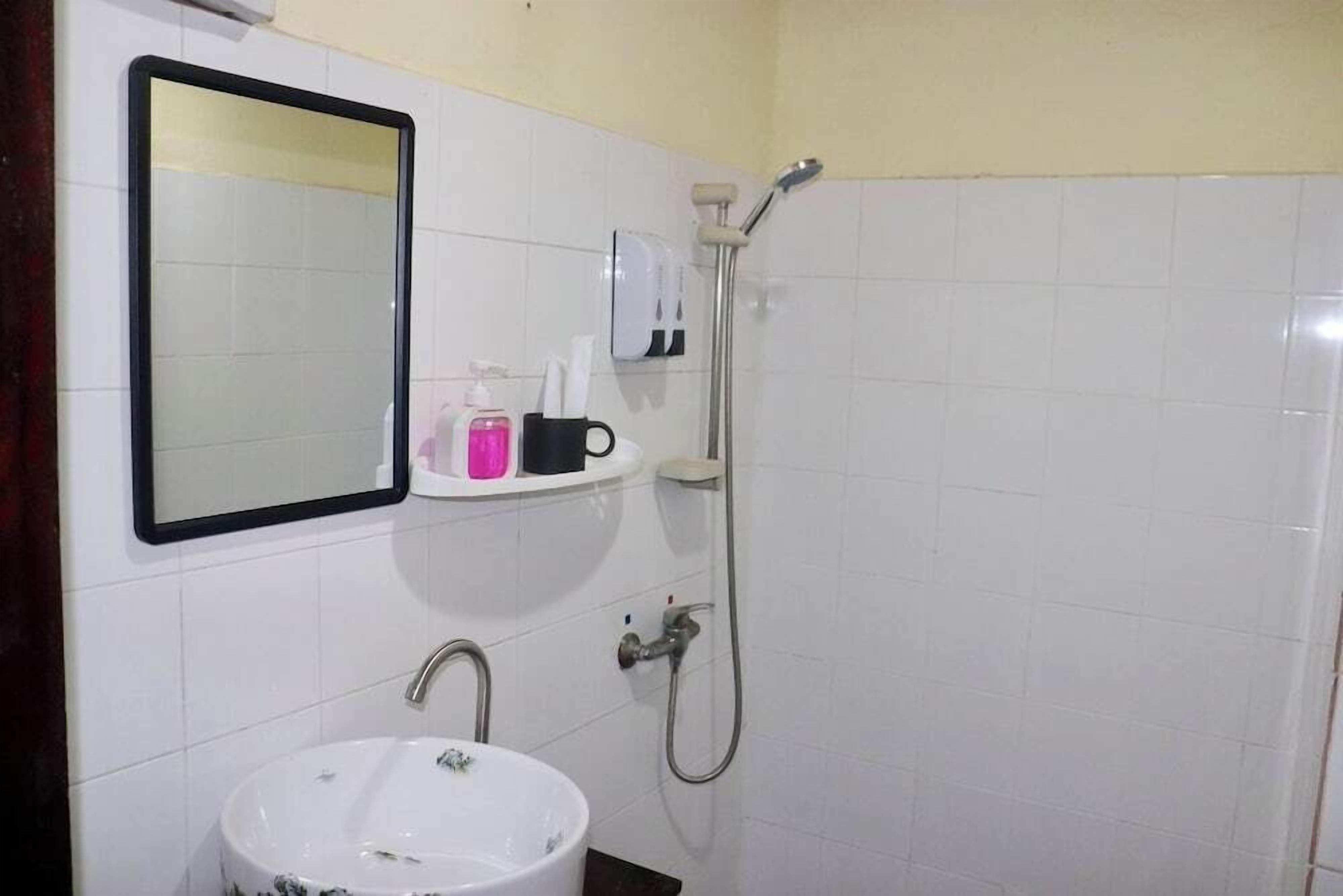 A bathroom with a sink, mirror, and shower.