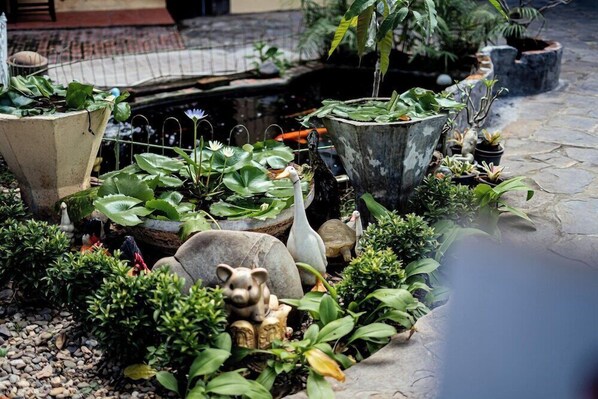 A garden with various plants, a pond, and decorative elements like a pig statue and a turtle. - Khoum Xieng Thong Boutique Villa (Luang Prabang)