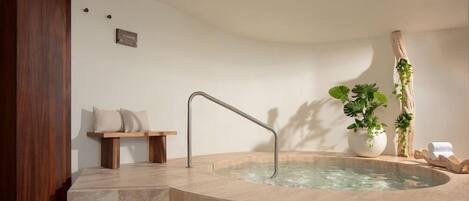 A spa area with a hot tub, wooden steps, a bench, and potted plants.