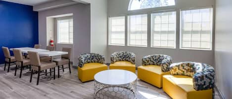 A modern interior with a dining area, yellow sofas, and a large window providing natural light.