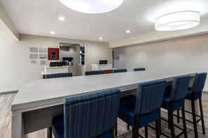 Una sala de conferencias moderna con una mesa larga y sillas tapizadas en azul, equipada con una computadora portátil y un armario rojo.