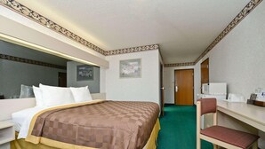 A hotel room with a bed, a desk, a chair, a mirror, and a door. - Microtel Inn & Suites by Wyndham Sunbury/columbus North (Sunbury)