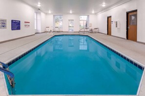 A swimming pool with clear water, surrounded by a tiled deck, and equipped with lounge chairs and a pool table. - Microtel Inn & Suites by Wyndham Sunbury/columbus North (Sunbury)