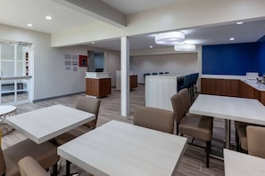 A modern hotel lobby with a reception desk, seating area, and a view of the kitchen in the background. - Microtel Inn & Suites by Wyndham Sunbury/columbus North (Sunbury)