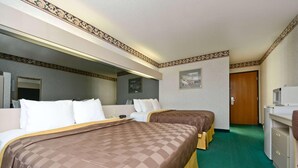 A hotel room with two beds, a desk, a mirror, and a door.