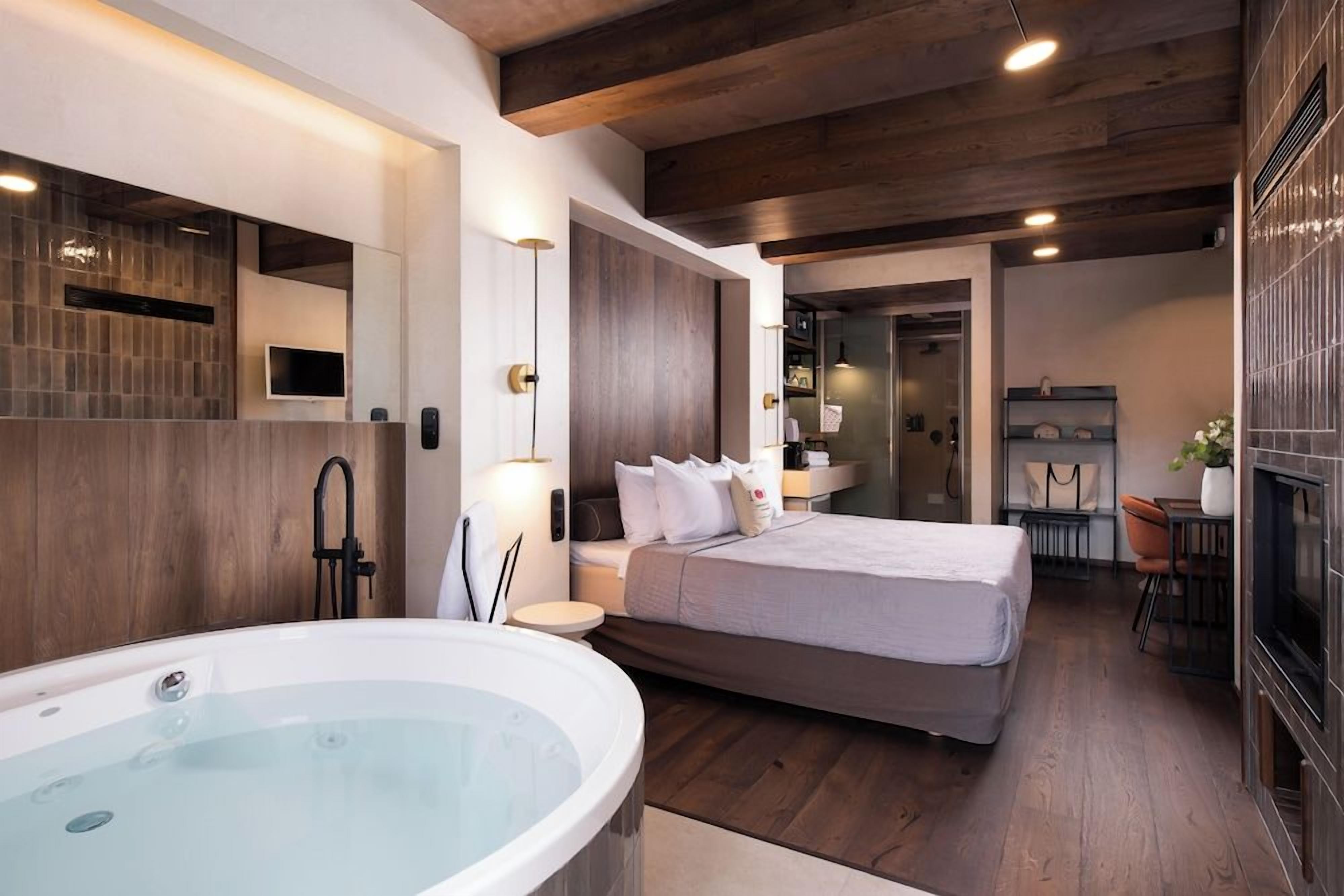 Un dormitorio moderno con una cama grande, una bañera integrada y un televisor.