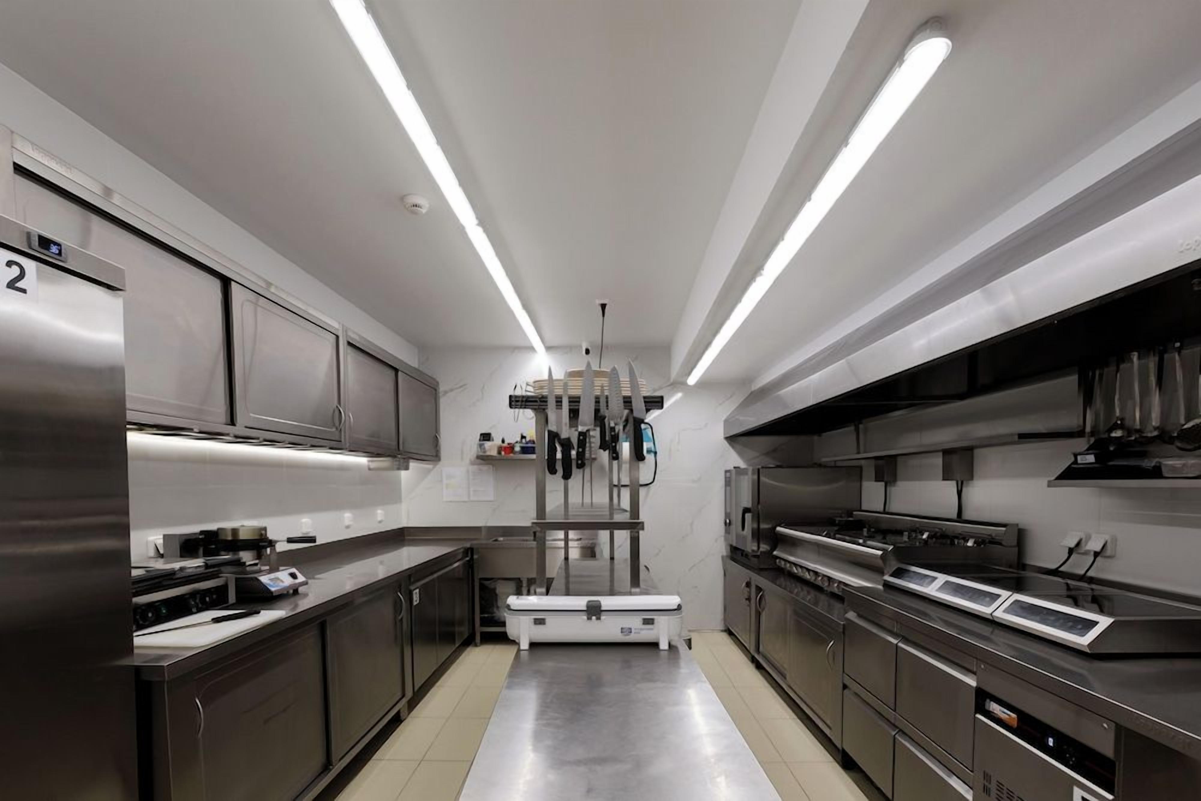 Una cocina moderna con electrodomésticos de acero inoxidable, una isla central e iluminación colgante.