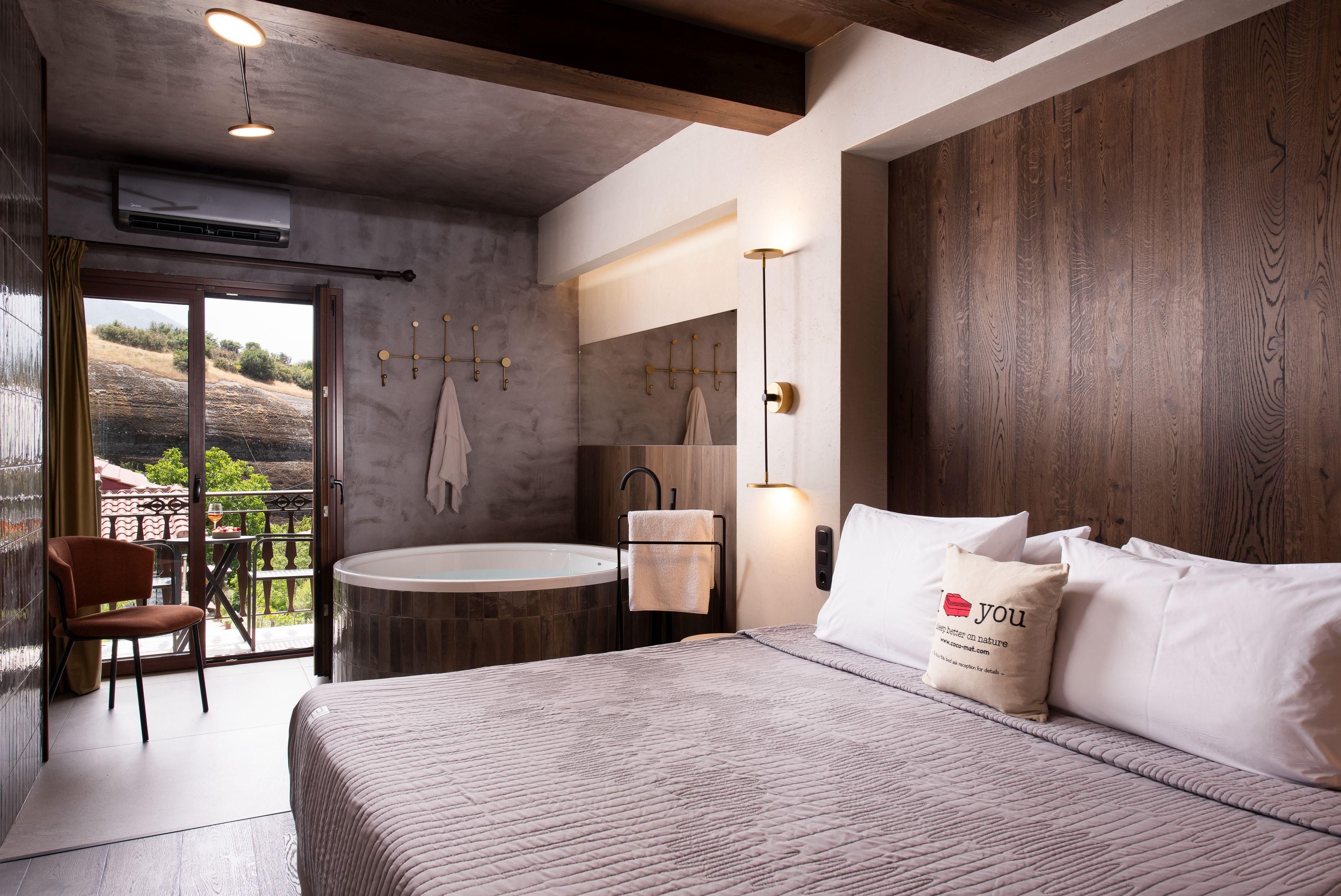 Ein modernes Schlafzimmer mit einem großen Bett, einer runden Badewanne und einem Balkon mit Blick.