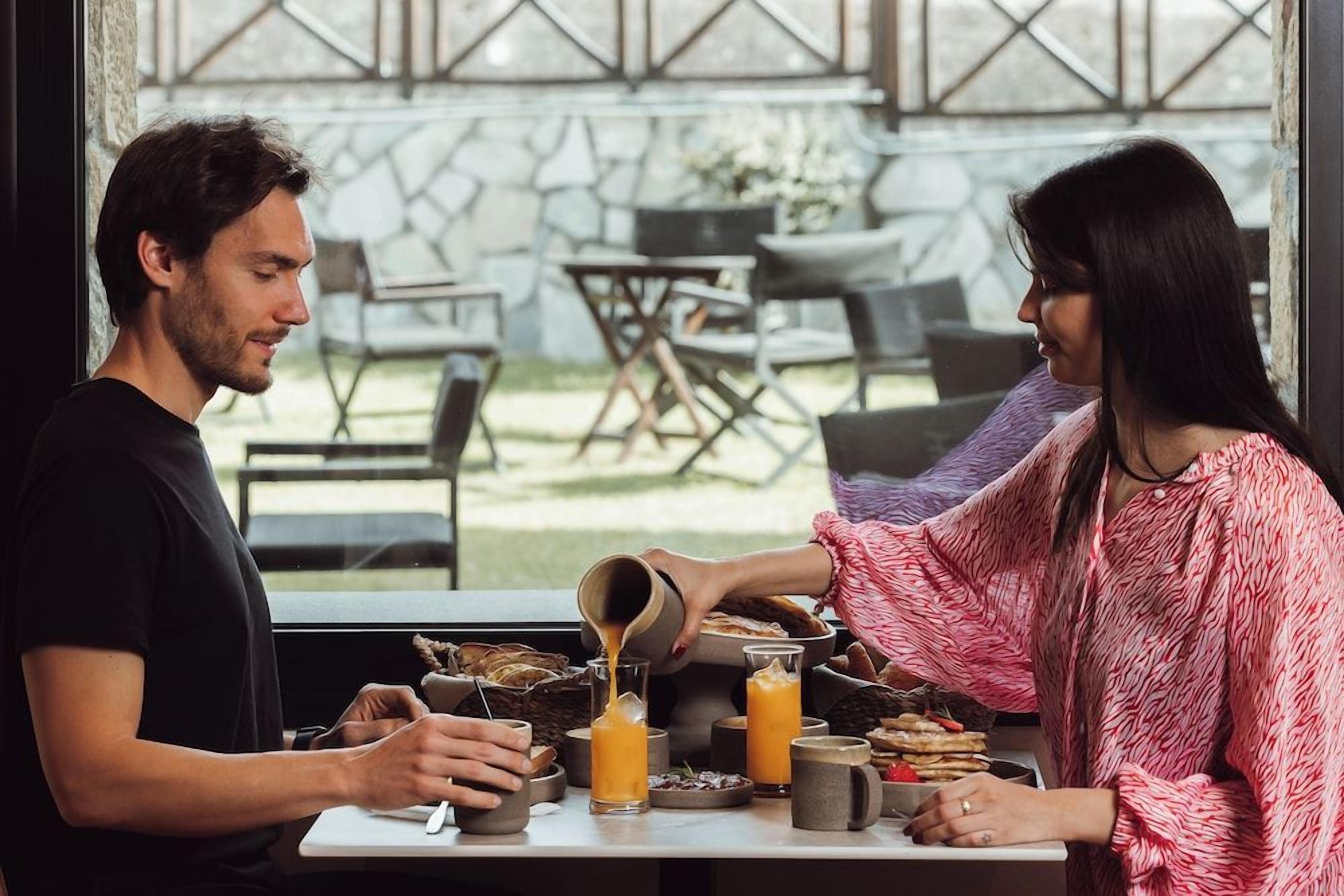 Una escena de desayuno con una mesa, sillas y vistas al exterior.