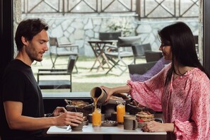 Una escena de desayuno con una mesa, sillas y vistas al exterior.