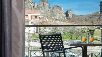 Una mesa con dos vasos de jugo de naranja, una silla y vistas a formaciones rocosas y un edificio.