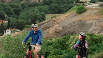 Dos ciclistas en un sendero de grava con montañas al fondo.