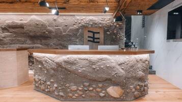 Un mostrador de recepción con fachada de piedra, techo de madera y diseño minimalista.