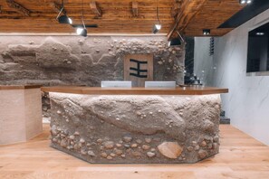 Un mostrador de recepción con fachada de piedra, techo de madera y diseño minimalista.