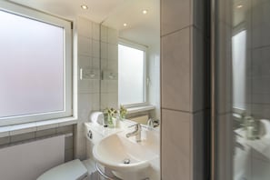 Ein modernes Badezimmer mit großem Fenster, zwei Waschbecken, einem Spiegel und einer Toilette.