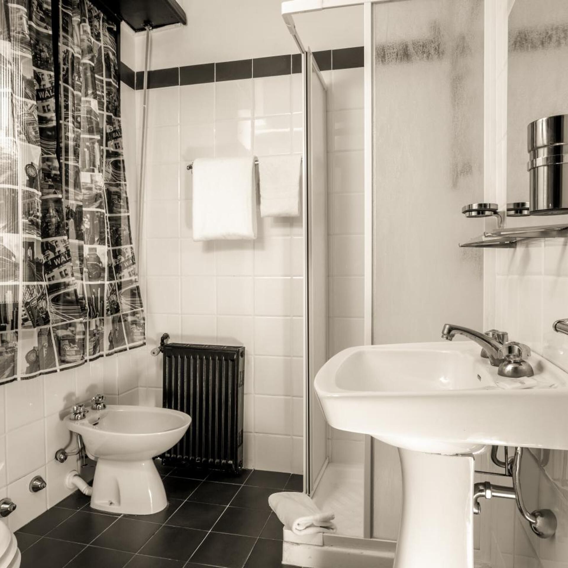 A bathroom with a toilet, bidet, shower, and sink.