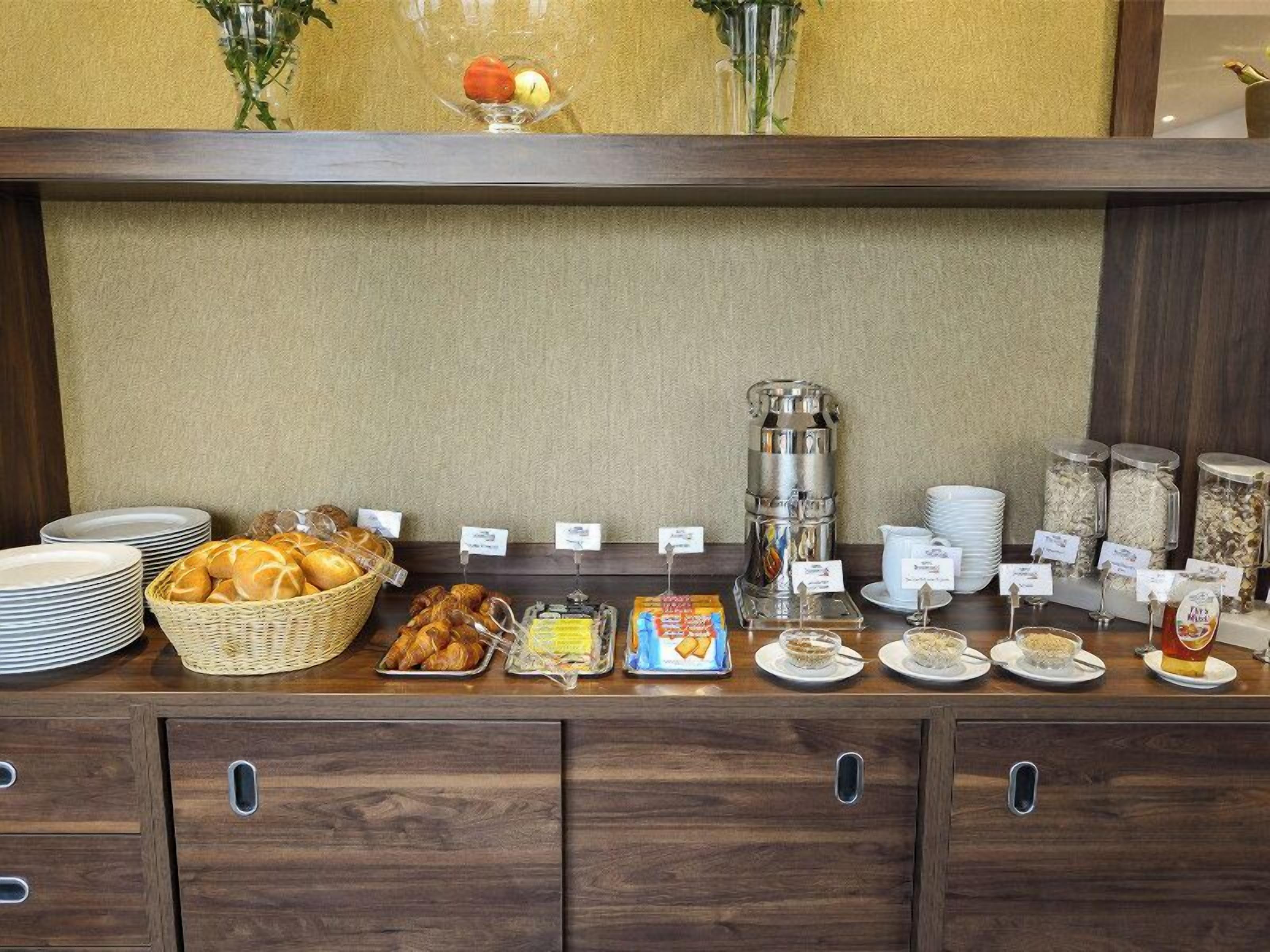 A buffet setup with bread, pastries, and various breakfast items.